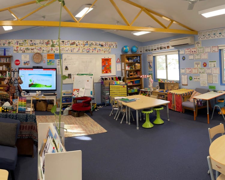 a classroom with plants and tables, learning screen and boards